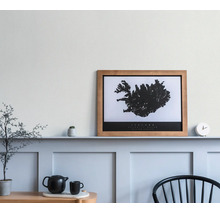 Houten fotolijst met een zwart-witte kaart van IJsland op een wandplank in een lichte, minimalistische kamer.