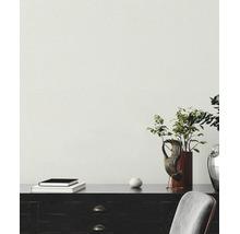Structuurbehang in een moderne kamer met een donker bureau, boeken, een handsculptuur en een plant.