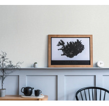 Ingelijste zwart-wit kaart van IJsland in een houten lijst, op een plank in een lichte kamer met wandpanelen.