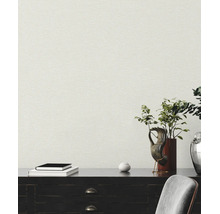 Gestructureerd vliesbehang met linnenlook op een muur achter een donker dressoir met decoratie en boeken.