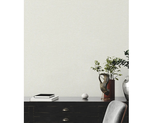 Gestructureerd vliesbehang met linnenlook op een muur achter een donker dressoir met decoratie en boeken.