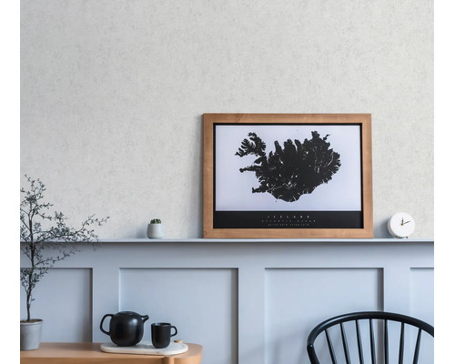 Een ingelijste wandkaart van IJsland op een plank in een minimalistische kamer met lambrisering, een klok en een theepot.