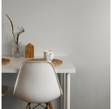 Moderne werkplek met wit bureau en stoel tegen een grijze muur met textuur. Versierd met een glazen vaas, houten decoratie en een mok.