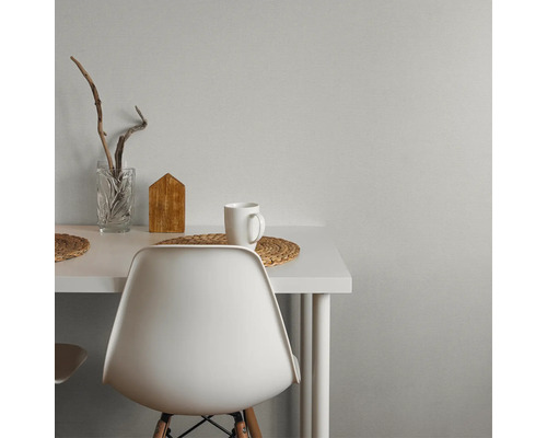 Moderne werkplek met wit bureau en stoel tegen een grijze muur met textuur. Versierd met een glazen vaas, houten decoratie en een mok.