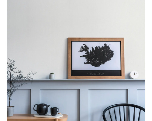 Ingelijste poster met kaart van IJsland in een houten lijst op een plank in een minimalistisch ingerichte kamer.