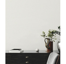 Lichte kamer met behang met textuur, dressoir met planten, boeken en decoratie, en een stoel.