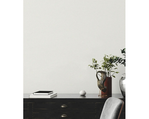 Lichte kamer met behang met textuur, dressoir met planten, boeken en decoratie, en een stoel.