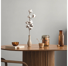Ronde houten tafel met een geribbelde zuilvoet, gedecoreerd met een vaas met katoentak, een voorraadpot, een glazen fles en een boek.