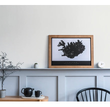 Houten fotolijst met kaart van IJsland op een wandplank in een lichte kamer met wandpanelen.