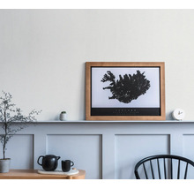 Ingelijste poster met kaart van IJsland in houten lijst op een plank in een lichte, modern ingerichte kamer met wandpanelen en decoratie.