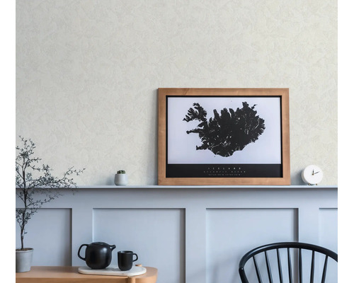 Ingelijste kaart van IJsland in een houten lijst, op een plank boven wandpanelen in een lichte, modern ingerichte kamer.