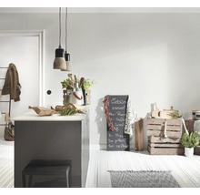 Lichte keuken met grijs kookeiland, betonnen hanglampen, houten keukengerei, een krijtbord en houten kratten op een lichte vloer.