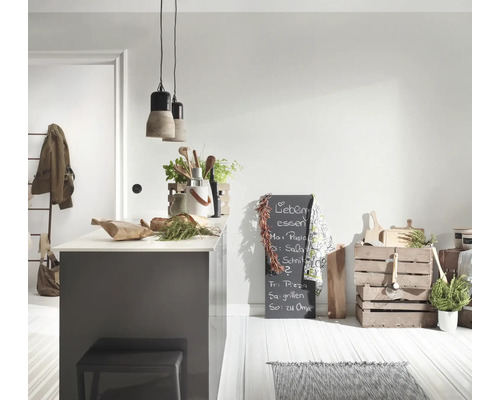Lichte keuken met grijs kookeiland, betonnen hanglampen, houten keukengerei, een krijtbord en houten kratten op een lichte vloer.