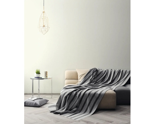 Lichte woonkamer met crèmekleurige muur, bank met gestreepte deken, bijtafel en geometrische hanglamp op een parketvloer.