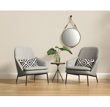Lichte woonkamer met twee grijze fauteuils, kussens met geometrisch patroon, een ronde bijzettafel en een ronde wandspiegel.