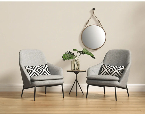 Lichte woonkamer met twee grijze fauteuils, kussens met geometrisch patroon, een ronde bijzettafel en een ronde wandspiegel.