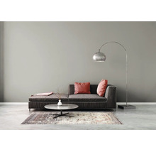 Moderne woonkamer met een donkere stoffen bank, rode kussens, een ronde marmeren salontafel, een gedessineerd tapijt en een zilveren booglamp.