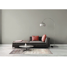 Moderne woonkamer met donkergrijze bank, booglamp, ronde salontafel en een gedessineerd vloerkleed tegen een grijze wand.