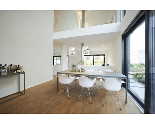 Moderne, lichte eetkamer met grote tafel, witte stoelen, twee metalen hanglampen, houten parketvloer en glazen schuifdeuren tot aan het plafond.