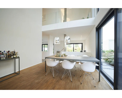 Moderne, lichte eetkamer met grote eettafel, zes witte stoelen, zilveren hanglampen, houten parketvloer en grote glazen schuifdeur.