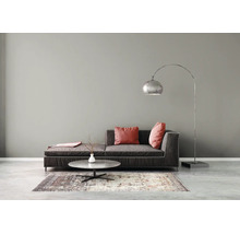 Minimalistische woonkamer met een donkere stoffen bank, een ronde stenen salontafel op een vloerkleed en een grote gebogen metalen vloerlamp.