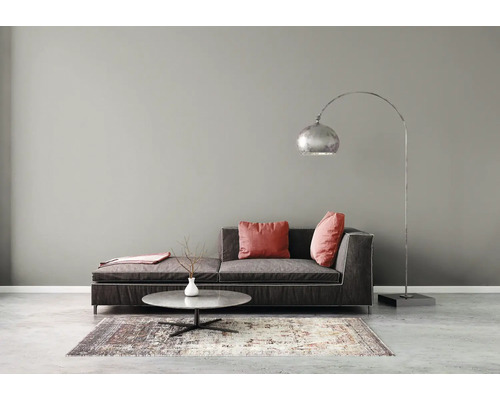 Minimalistische woonkamer met een donkere stoffen bank, een ronde stenen salontafel op een vloerkleed en een grote gebogen metalen vloerlamp.