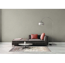 Moderne woonkamer met een grijze muur met textuur, donkergrijze bank, roze kussens, salontafel en een grote metalen booglamp.