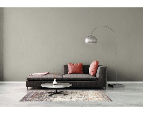 Moderne woonkamer met een grijze muur met textuur, donkergrijze bank, roze kussens, salontafel en een grote metalen booglamp.