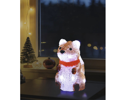 Verlichte acrylfiguur eekhoorn met rode sjaal op een tafel, kerstdecoratie voor binnen met kerstboom op de achtergrond.