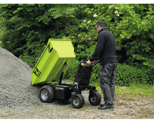 Een man leegt een Zipper motorkruiwagen met kiepmechanisme op een grindhoop in de tuin. Functionele, lichte buitenomgeving. Zipper Logo.