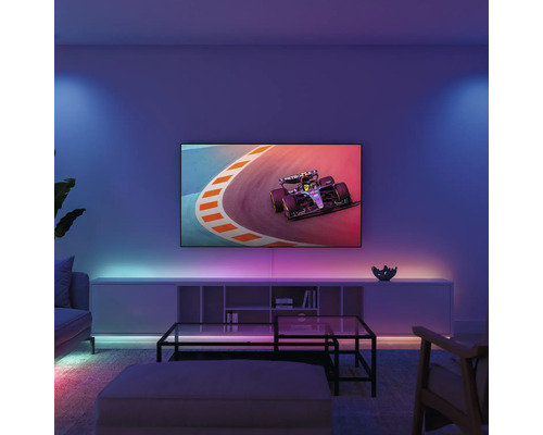 Moderne woonkamer met een televisie aan de wand die een raceauto toont, LED-sfeerverlichting achter de meubels en een glazen tafel.