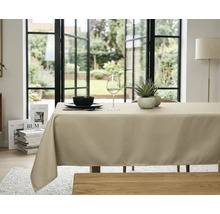 Beige tafelkleed op een eettafel in een lichte, georganiseerde kamer met grote glazen deuren en uitzicht op de tuin.