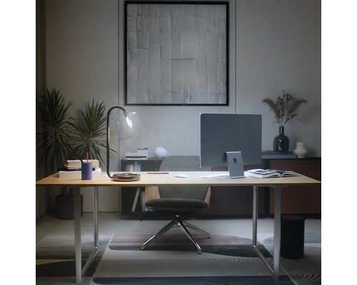 Modern thuiskantoor met licht houten bureau, monitor, glazen bureaulamp en ergonomische bureaustoel in een opgeruimde sfeer.