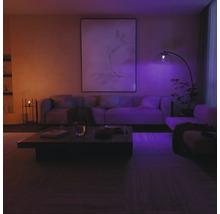 Moderne woonkamer met bank, salontafel en booglamp, verlicht door slimme verlichting.