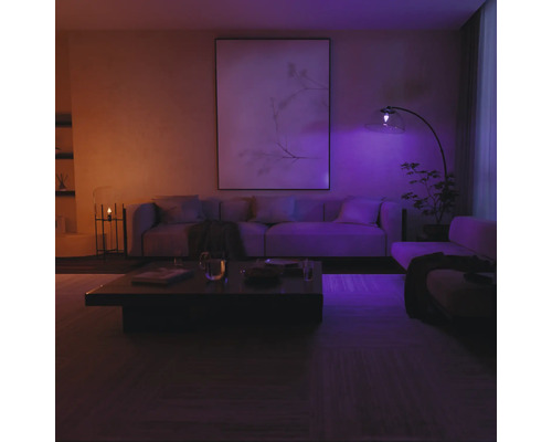 Moderne woonkamer met bank, salontafel en booglamp, verlicht door slimme verlichting.