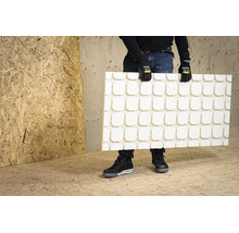 Persoon houdt een witte gestructureerde plaat met een vierkant patroon vast voor een wand van OSB-platen.