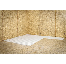 Witte systeemplaat met groeven voor vloerverwarming gelegd op OSB-platen in een hoek van de kamer.