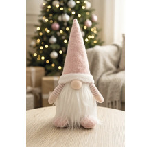 Stoffen kabouter met puntmuts en baard op een houten tafel in een lichte, feestelijk versierde kamer met een kerstboom.