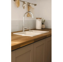 Lichte, moderne keuken met een inbouw dubbele spoelbak in een houten werkblad, een keukenkraan en keukenkastjes.