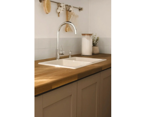 Lichte, moderne keuken met een inbouw dubbele spoelbak in een houten werkblad, een keukenkraan en keukenkastjes.
