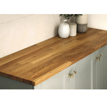 Massief houten keukenwerkblad van eiken op een onderkast met metalen handgrepen en decoratieve potten, moderne en georganiseerde sfeer.