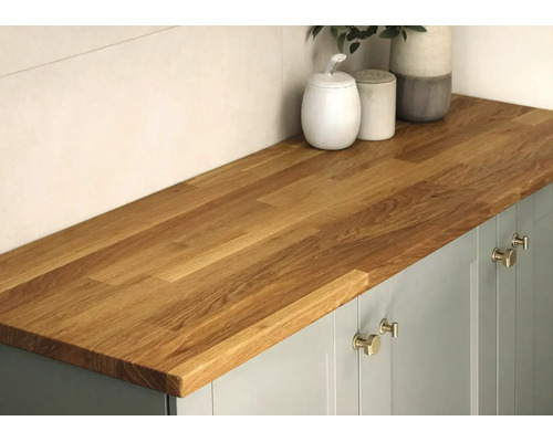 Massief houten keukenwerkblad van eiken op een onderkast met metalen handgrepen en decoratieve potten, moderne en georganiseerde sfeer.