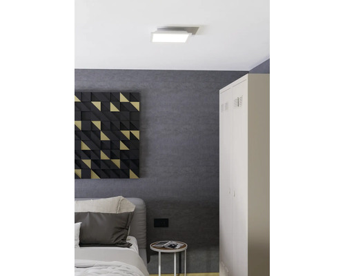 Vierkante LED-plafondlamp in een moderne kamer met gestructureerde wanden, een metalen kast, bed en geometrische wanddecoratie.