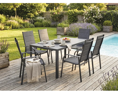 Moderne tuinset met een rechthoekige tafel en zes stoelen op een houten terras naast een zwembad in een groene tuin.