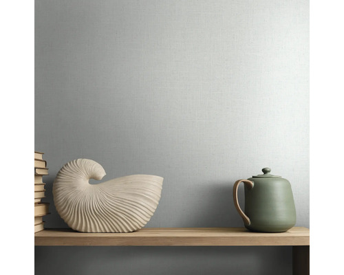 Behang met textuur en fijne linnenlook op een wand achter een houten plank met decoratieve objecten.