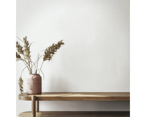 Minimalistisch interieur met een houten bank en een gestructureerde vaas met gedroogd rietgras voor een lichte muur.