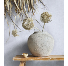 Gestructureerd behang met linnenlook op een muur achter een keramieken vaas met droogbloemen op een rustieke houten bank.