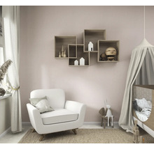 Lichte, georganiseerde kinderkamer met een witte fauteuil, een babybedje met hemeltje en in elkaar grijpende houten wandplanken aan een roze muur.