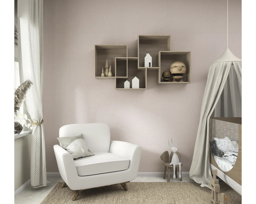 Lichte, georganiseerde kinderkamer met een witte fauteuil, een babybedje met hemeltje en in elkaar grijpende houten wandplanken aan een roze muur.