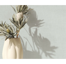 Gestructureerd behang met linnenlook op een muur met een vaas met droogbloemen en schaduwen.